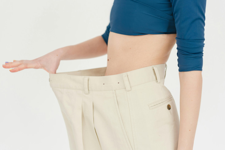 Woman shows weight loss progress with oversized clothing