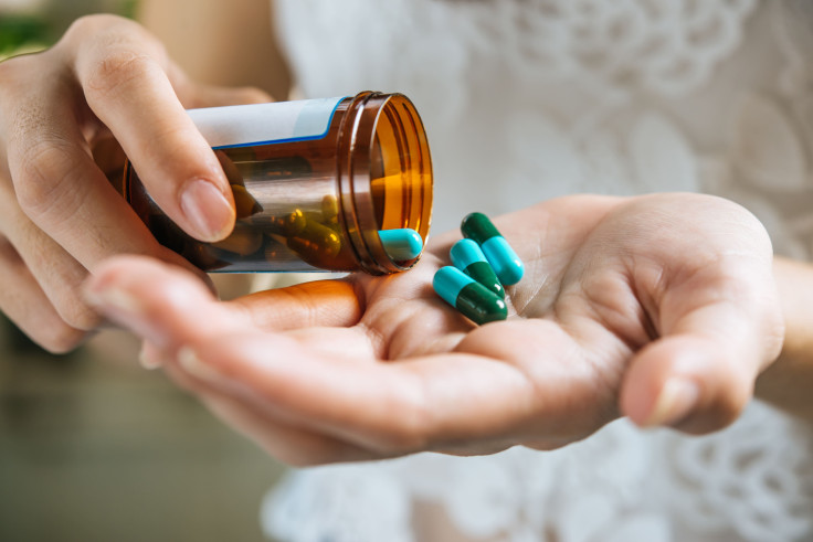 Woman's Hand Pours Medicine Pills Out Bottle