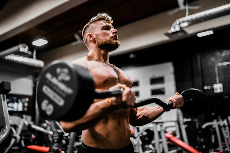 Man in a black short carrying a black dumbbell