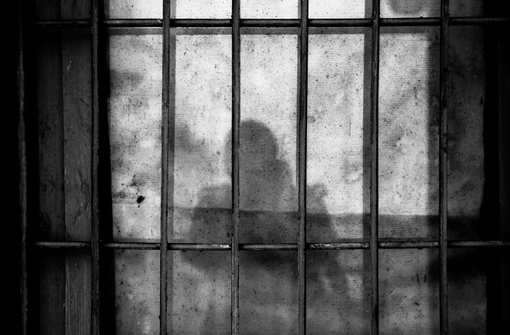 A shadow of a person behind bars in a jail