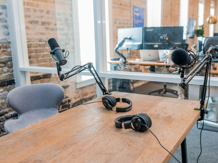 Two black headphones on brown wooden table