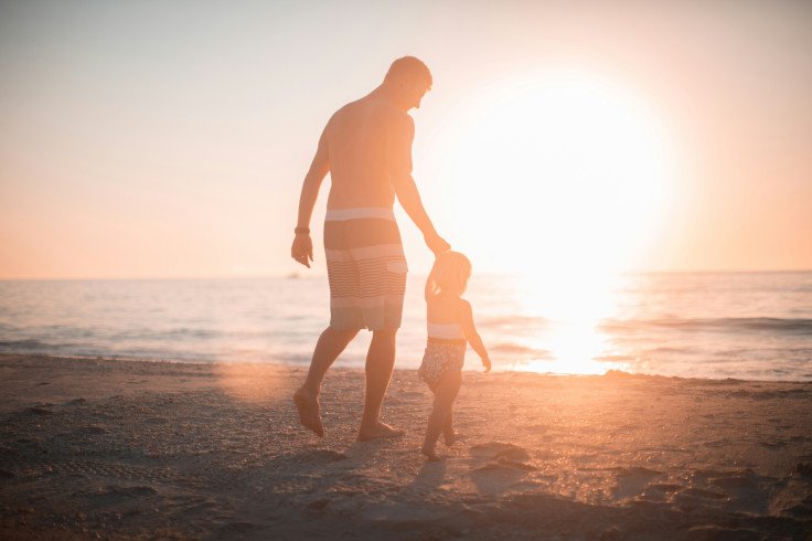 A man holding a girl heading towards the sea