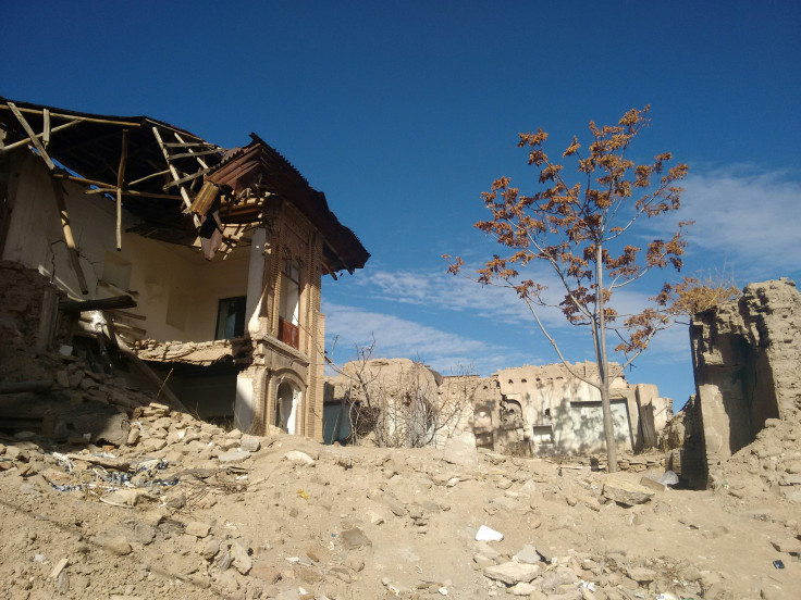 A broken building with a tree growing beside it