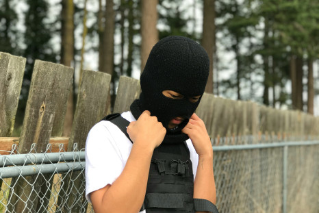 A person wearing a black mask and a black vest