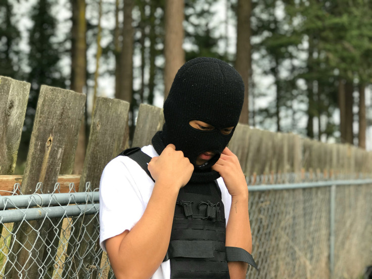 A person wearing a black mask and a black vest