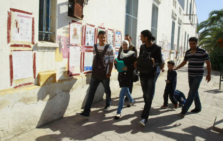 People walk past election posters in Tunis