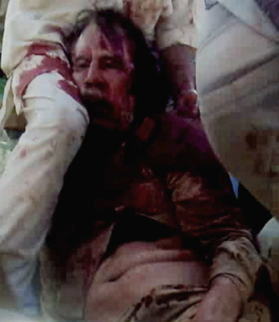 Frame grab of former Libyan leader Muammar Gaddafi, covered in blood, being held on the ground by NTC fighters in Sirte
