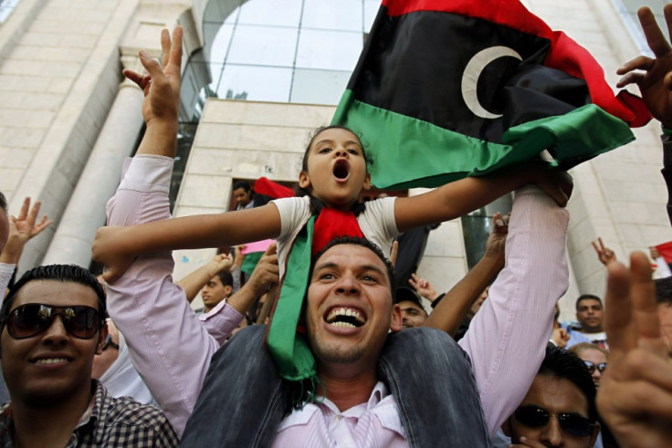 Libyan refugees in Tunisia celebrate after hearing news that Libyan leader Muammar Gaddafi was killed in Sirte, outside their embassy in Tunis