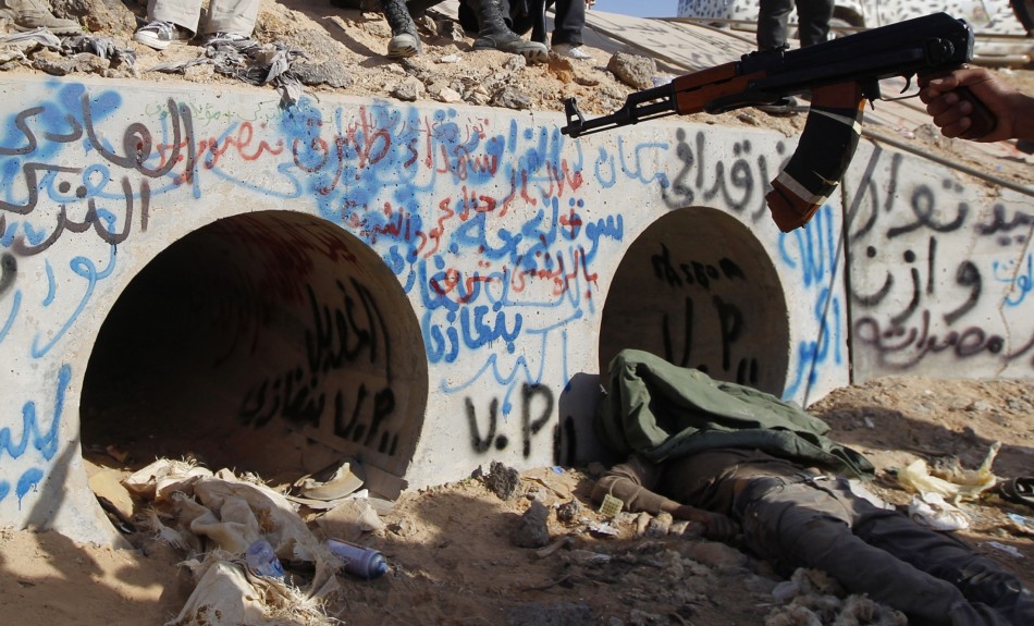 An anti-Gaddafi fighter points at the drain where Muammar Gaddafi was hiding before he was captured in Sirte