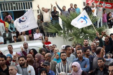 Supporters of the Islamist Ennahda movement hold party flags during Abdelhamid Jlazzi&#039;s speech outside the party&#039;s headquarters in Tunis