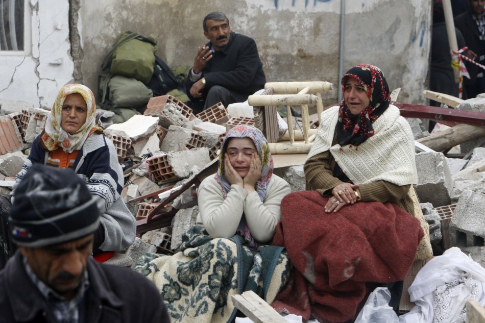 Earthquake survivors sit on the debris of a collapsed building in Ercis on Tuesday.