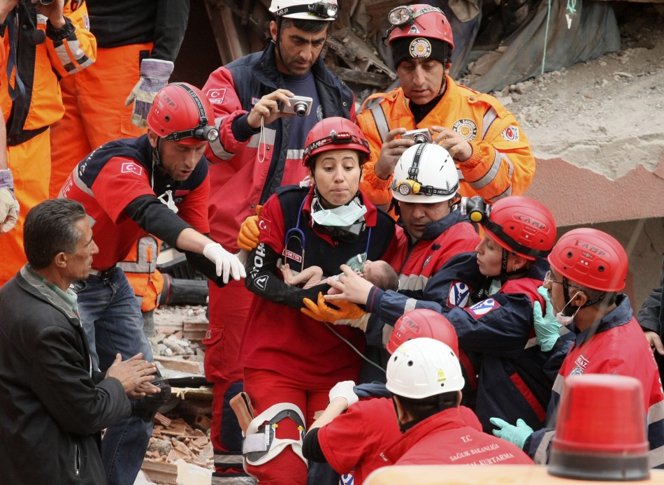 Rescue workers carry a 14-day-old newborn baby, which was rescued alive 46 hours after the earthquake, from the rubble of a collapsed building  in Ercis on Tuesday.