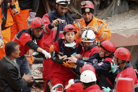 Rescue workers carry a 14-day-old newborn baby, which was rescued alive 46 hours after the earthquake, from the rubble of a collapsed building  in Ercis on Tuesday.