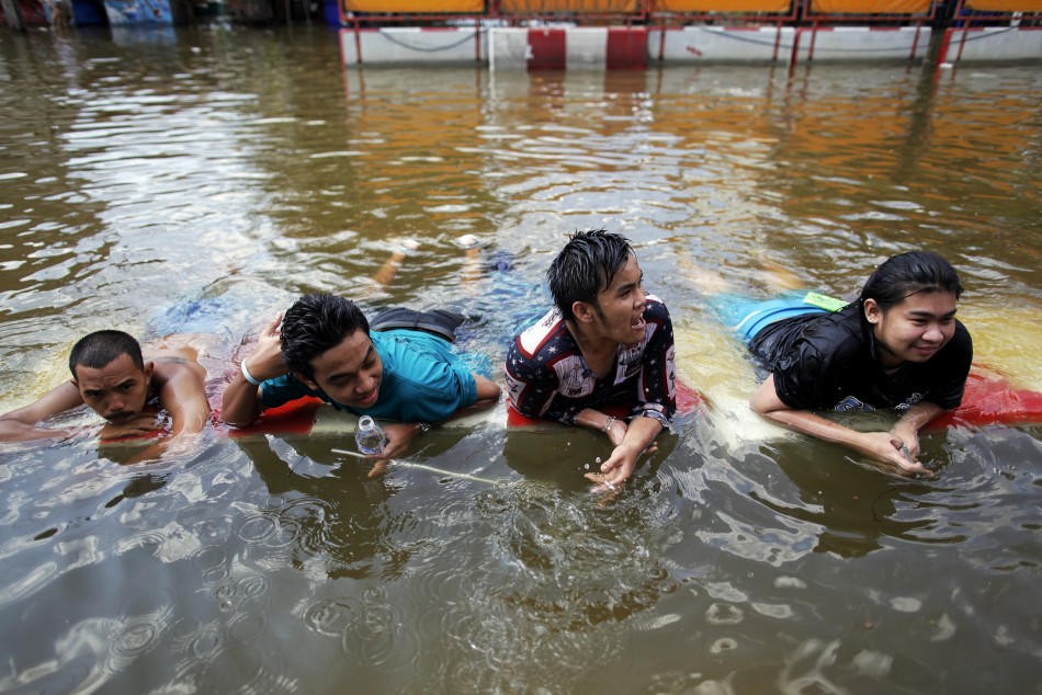 People take a break in water after floods advanced into their neighborhood near Chao Praya river in central Bangkok