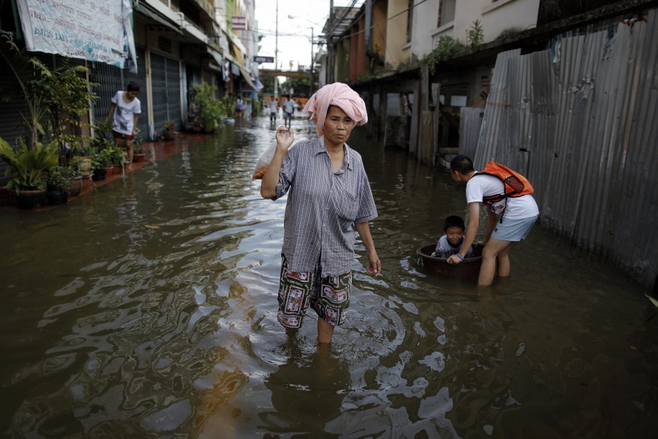 A woman carries food after floods advanced into her neighborhood near Chao Praya river in central Bangkok