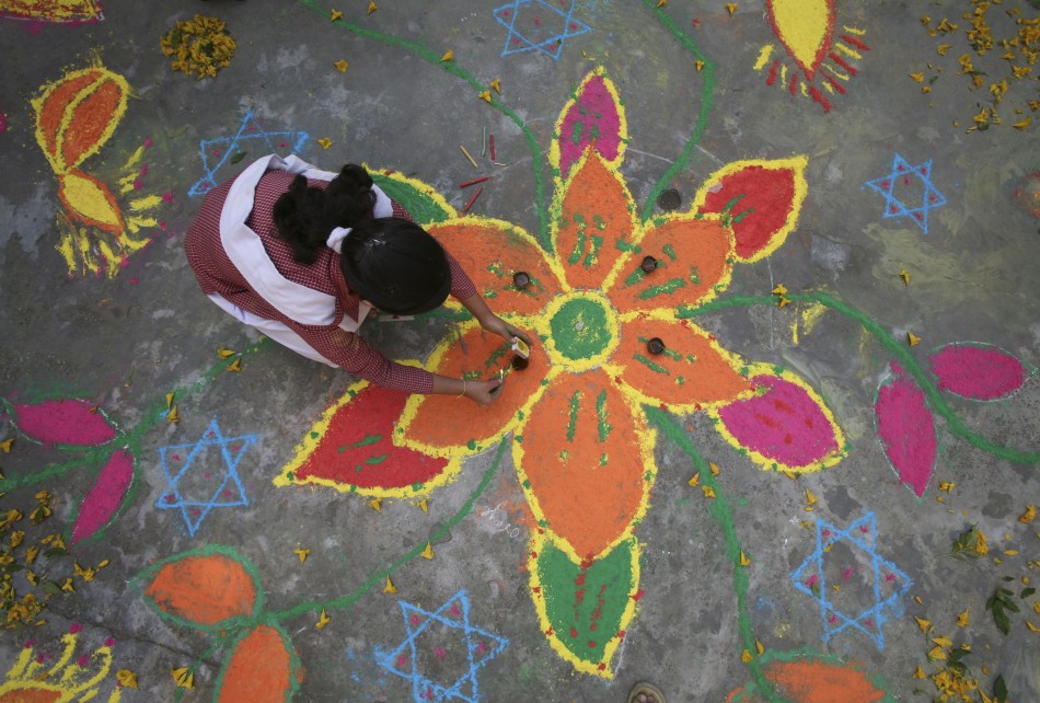 Students put the finishing touches to a rangoli, or a mural