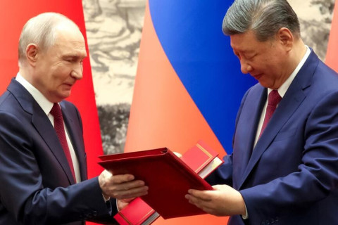 Putin and Xi exchange documents during their meeting