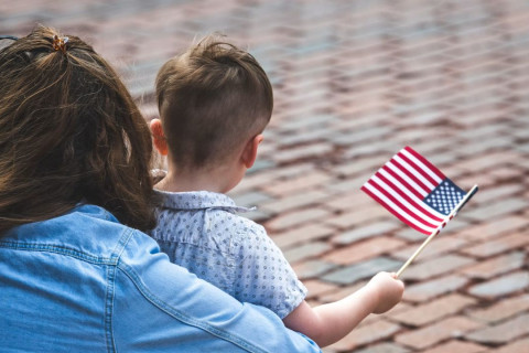 Woman and child holding small american flag.