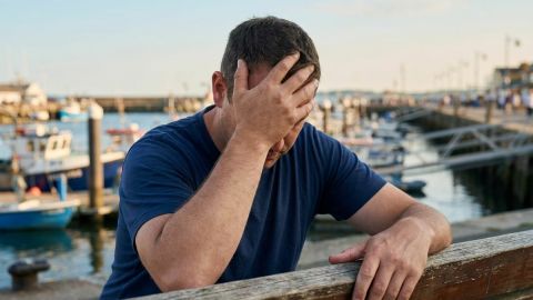 Stressed man with hand on forehead by harbour
