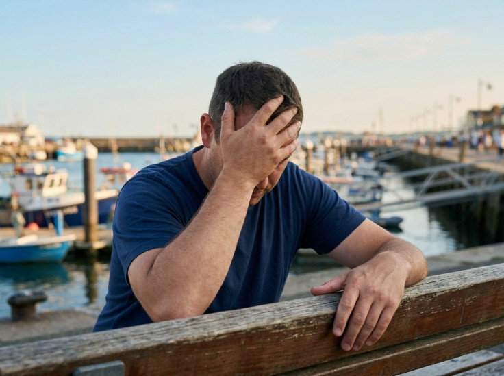 Stressed man with hand on forehead by harbour