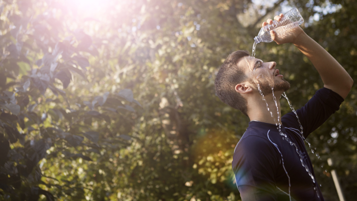 Man pours water on himself as the sun glares