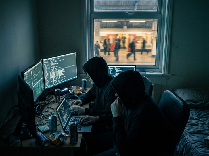 Two hooded young men sit in a dark