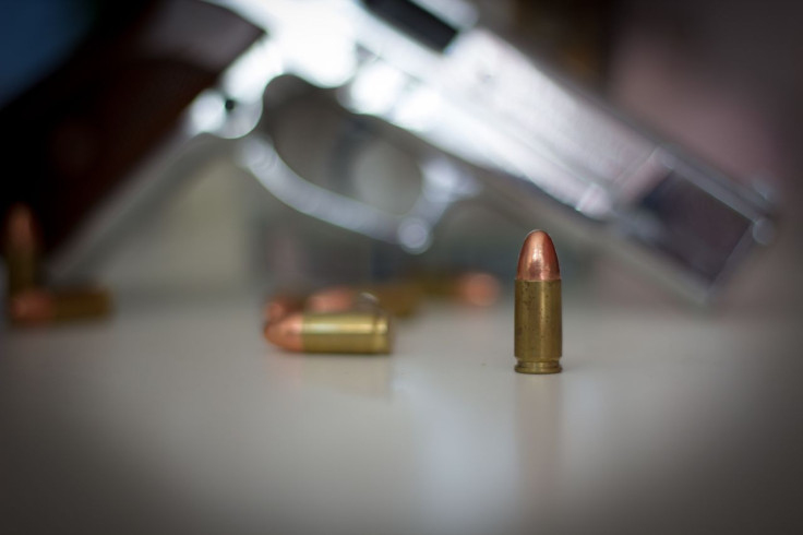 Close-up of bullets with gun in the background