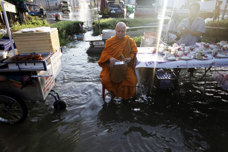 A Buddhist monks waits for morning alms at the flooded market outside the Grand palace in Bangkok
