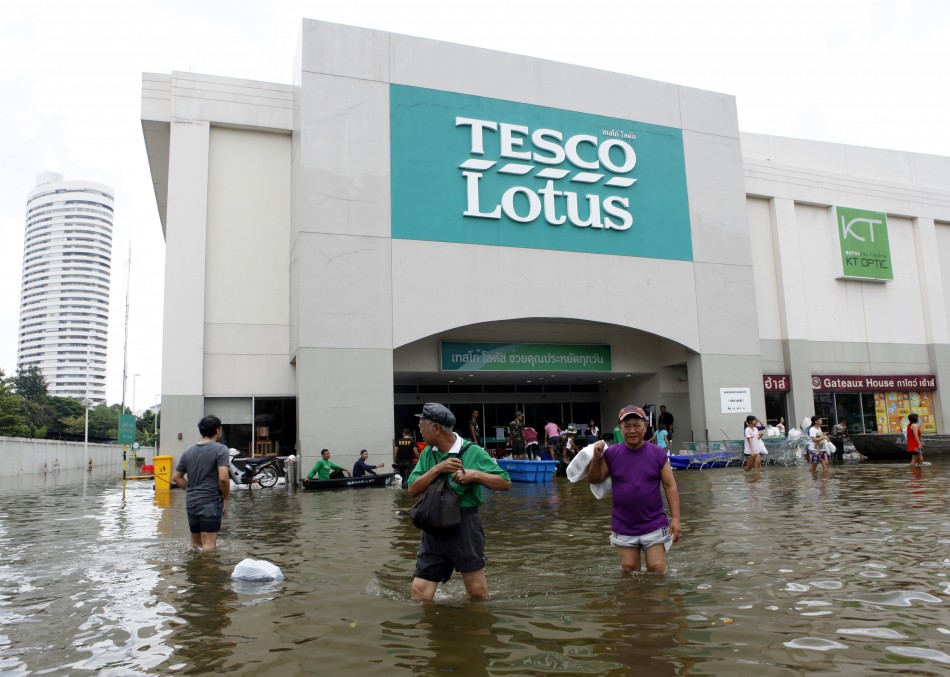 People wades through a flooded Tesco Lotus supermarket after they buy belongings at Bang Phlat district in Bangko