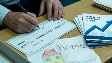 A council worker's hands signing a care placement cheque