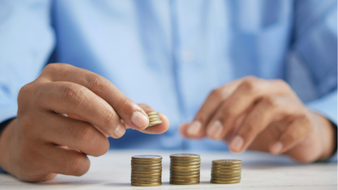 A person arranging stacks of coins of different heights