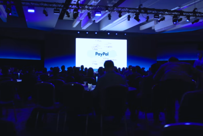 Audience at a conference with a PayPal presentation in the background