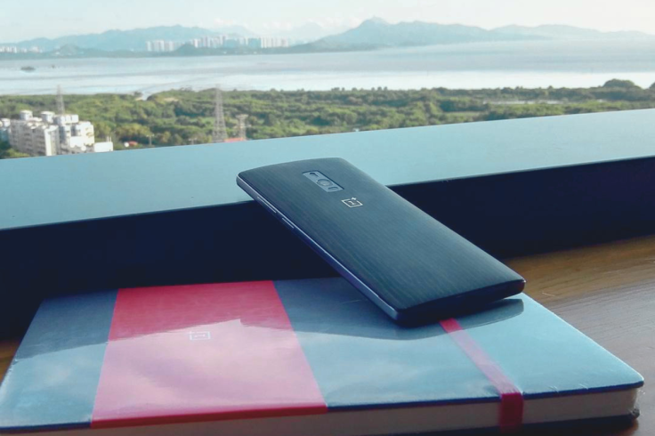 A OnePlus 2 handset resting on a red-banded notebook
