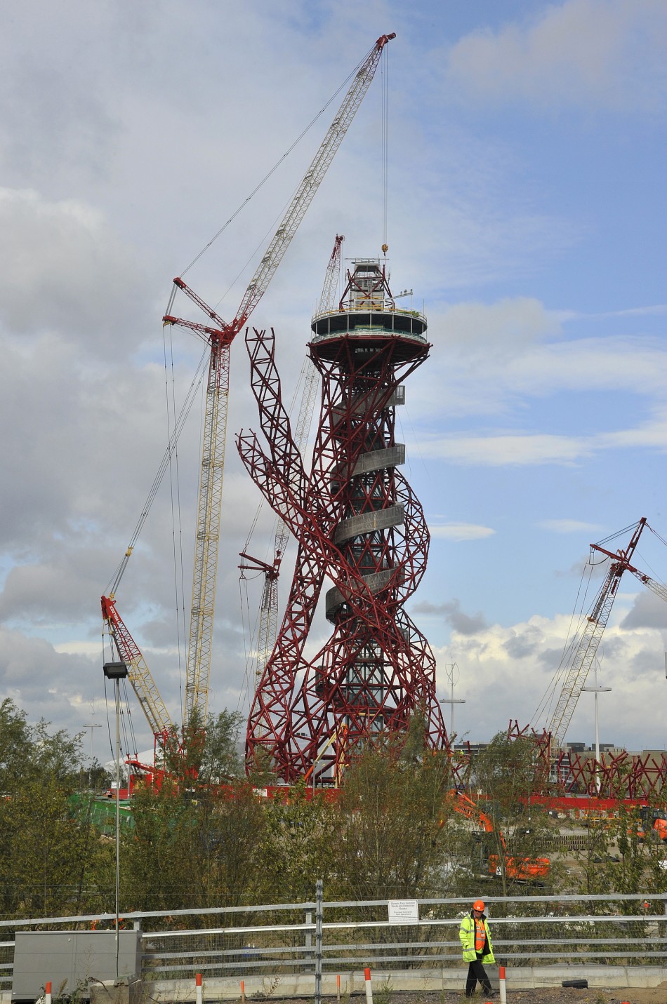 A construction worker passes near the Anish Kapoor-designed ArcelorMittal Orbit tower at the Olympic site at Stratford in east London, on October 7, 2011. The tower will be Britains largest piece of public art and is intended to form part of the legacy o