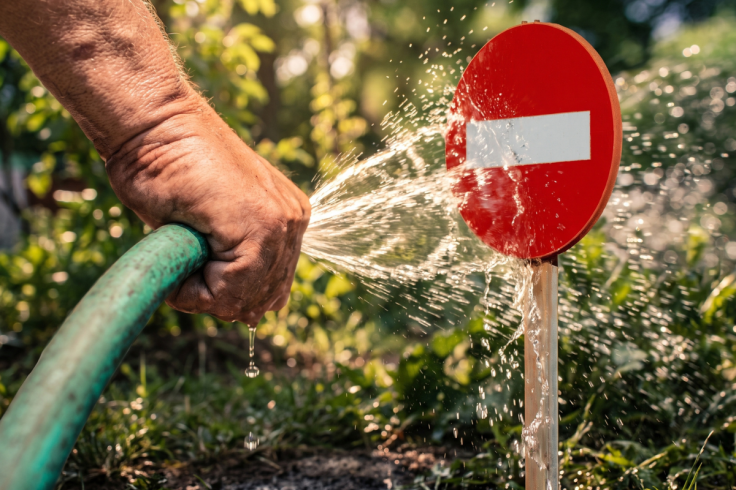 A garden hose spraying water at a red no entry