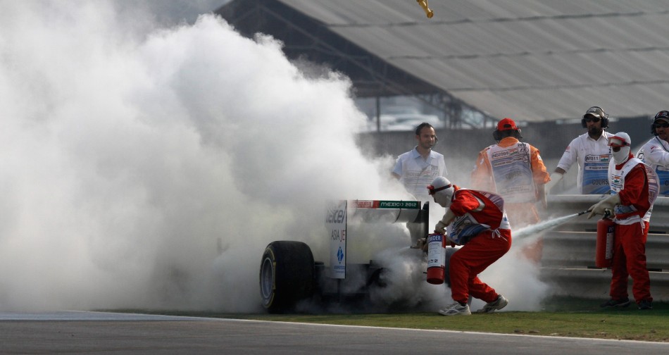 Course marshals use fire extinguishers on the car of Sauber Formula One driver Kamui Kobayashi