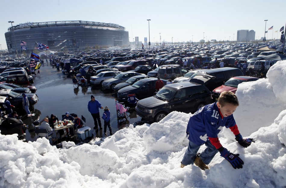 A boy climbs on a giant pile of snow in the parking lot at MetLife Stadium before NFL football game between Giants and Dolphins in East Rutherford