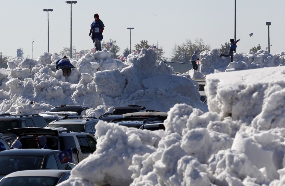 Football fans climb on giant piles of snow in the parking lot at MetLife Stadium before the NFL football game in East Rutherford