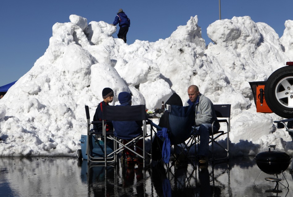 Football fans tailgate in the parking lot near a giant pile of snow at MetLife Stadium before the NFL football game in East Rutherford