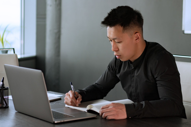 A professional man writes notes in a notebook