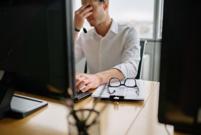 Man at office desk holding head in frustration