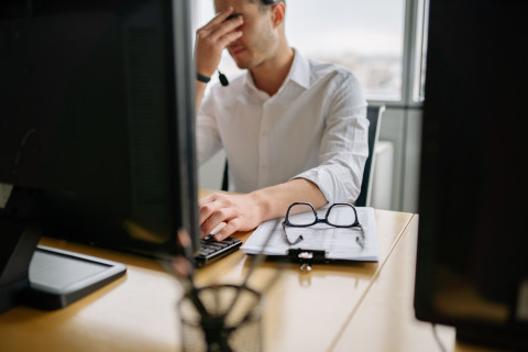 Man at office desk holding head in frustration