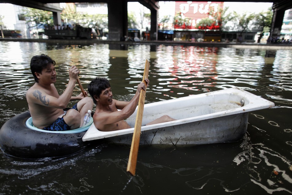 Men paddle their makeshift raft through a flooded street in central Bangkok