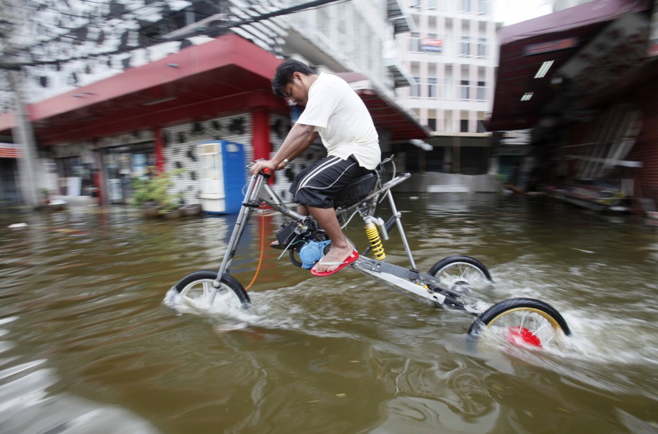 A flood victim cycles through the water using a homemade tall three-wheeler in Bang Phlad district, Bangkok