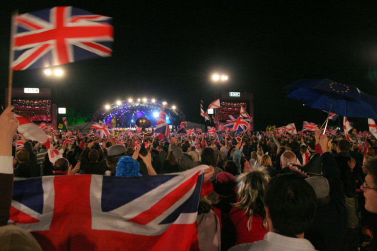 Citizens holding up British flags at nighttime.