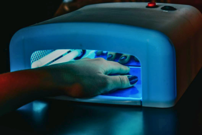 Manicured nails being cured under LED lamp for gel polish