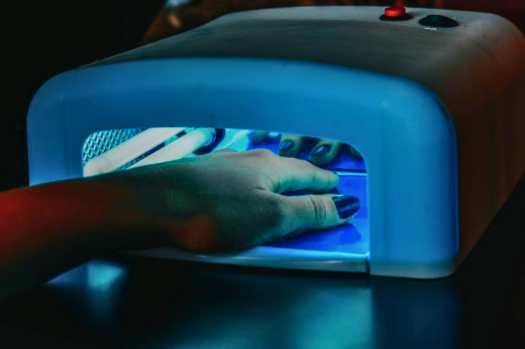 Manicured nails being cured under LED lamp for gel polish