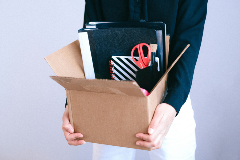 Person carries a box of belongings after losing their job.