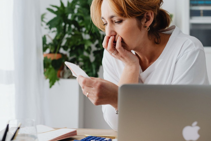 A woman sits at a home desk, savings, mortgage