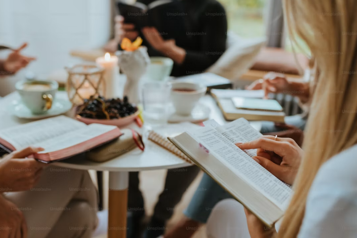 A group of people sitting around a table with books 